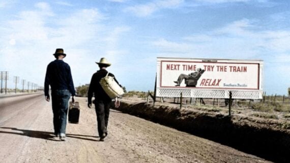Two men walk along a dirt road carrying bags, passing a billboard that reads, &ldquo;Next time, try the train. Relax. Southern Pacific,&rdquo; with an image of a man reclining on a train seat.