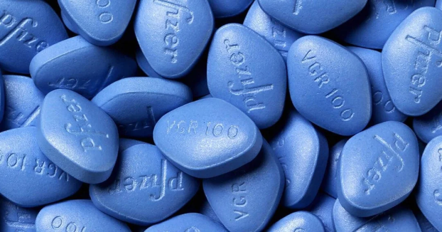 A pile of blue, diamond-shaped pills with "Pfizer" and "VGR 100" engraved on them, indicating they are Viagra tablets.