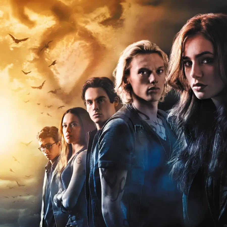 Five serious-looking young adults stand in a dramatic, dimly lit setting with a cloudy, golden sky and flying birds in the background. They wear dark clothing and have visible tattoos.