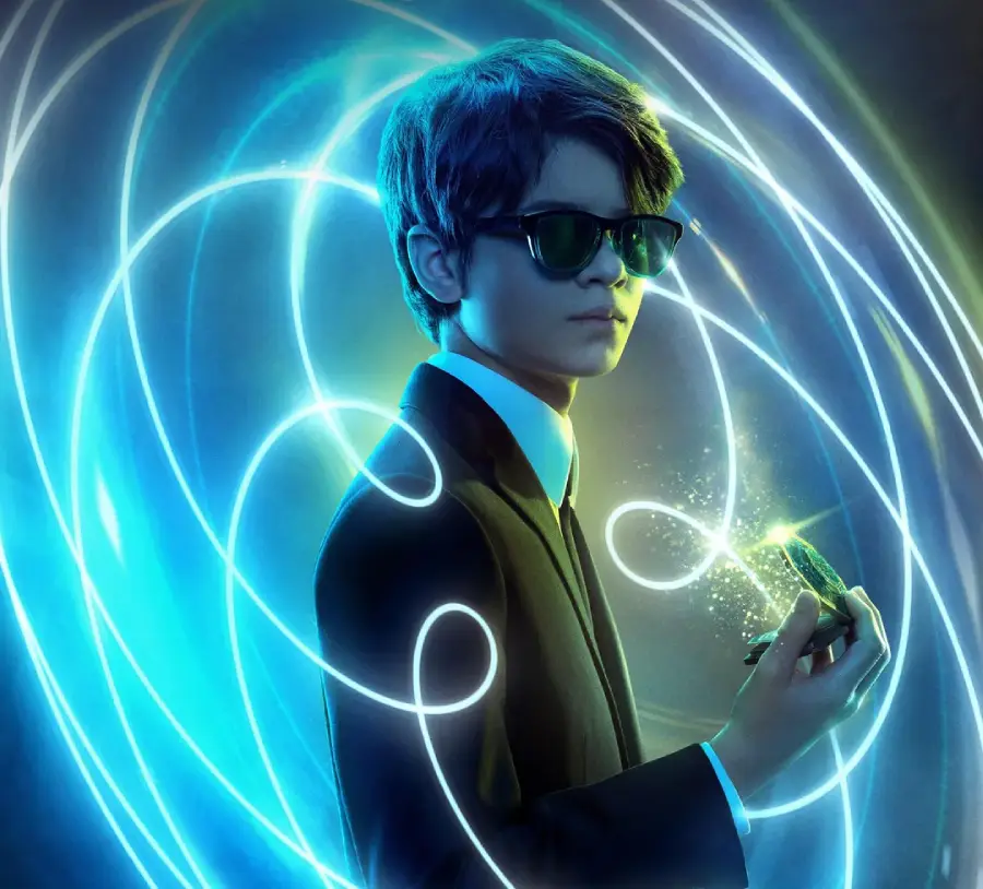 A boy in a black suit and sunglasses holds a glowing object, with swirling blue and green light trails surrounding him in a futuristic, magical atmosphere.