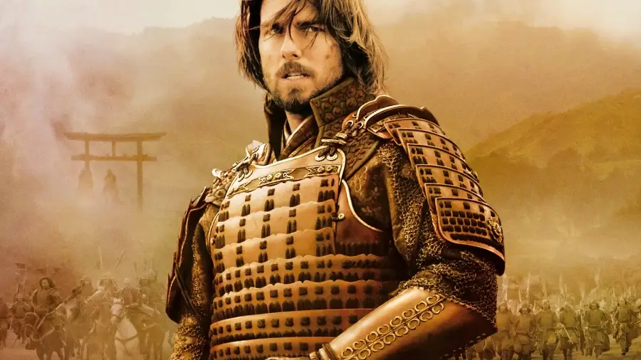 A man with long hair and a beard, wearing detailed samurai armor, stands in front of a hazy battlefield with soldiers and a traditional torii gate in the background. The scene has a golden, dramatic atmosphere.