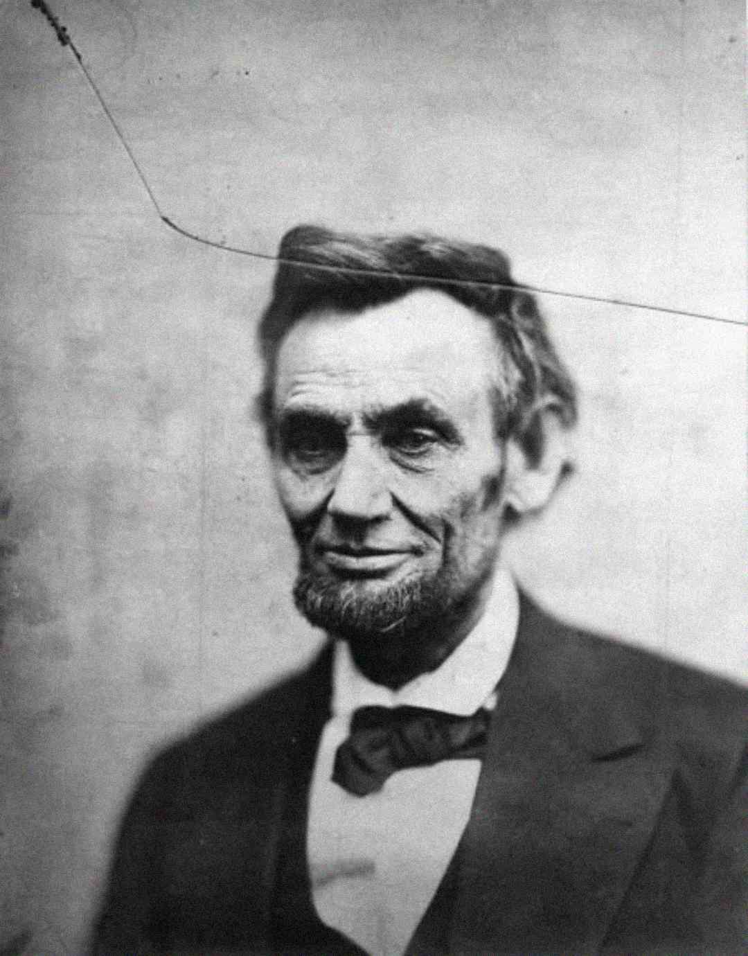 A black-and-white portrait of a man with a beard and no mustache, wearing a suit and bow tie, looking slightly to the side against a plain background.