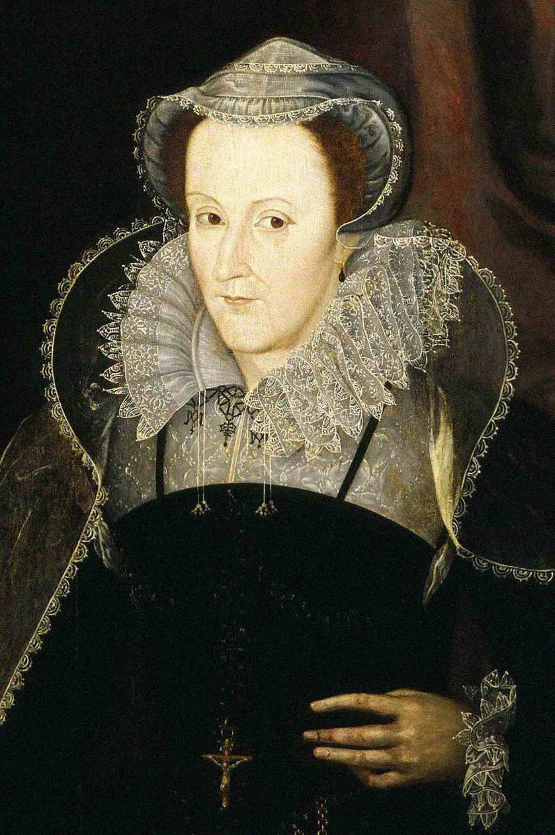 Portrait of a woman in elaborate 16th-century clothing, featuring a lace ruff collar, dark dress with embroidery, and a headpiece. She has a pale complexion and holds her hand near her waist. The background is dark.