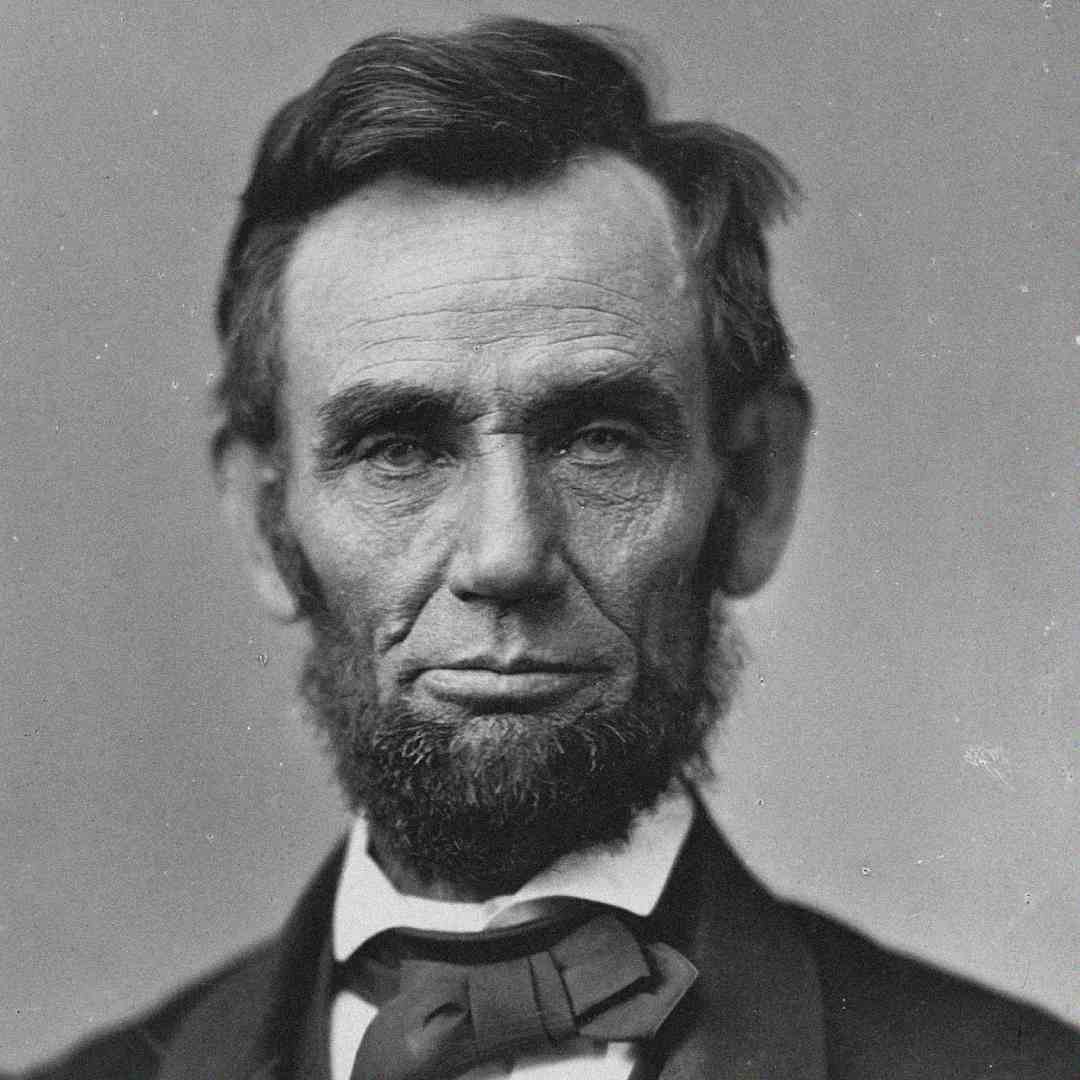 A black-and-white portrait photograph of a man with a beard, wearing a suit, white shirt, and bow tie, looking directly at the camera with a serious expression.