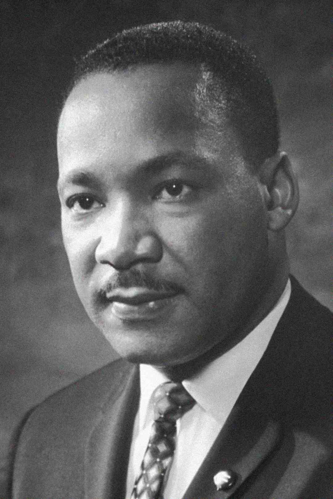 A black and white portrait of a man in a suit and tie, looking slightly to the side with a calm and composed expression.