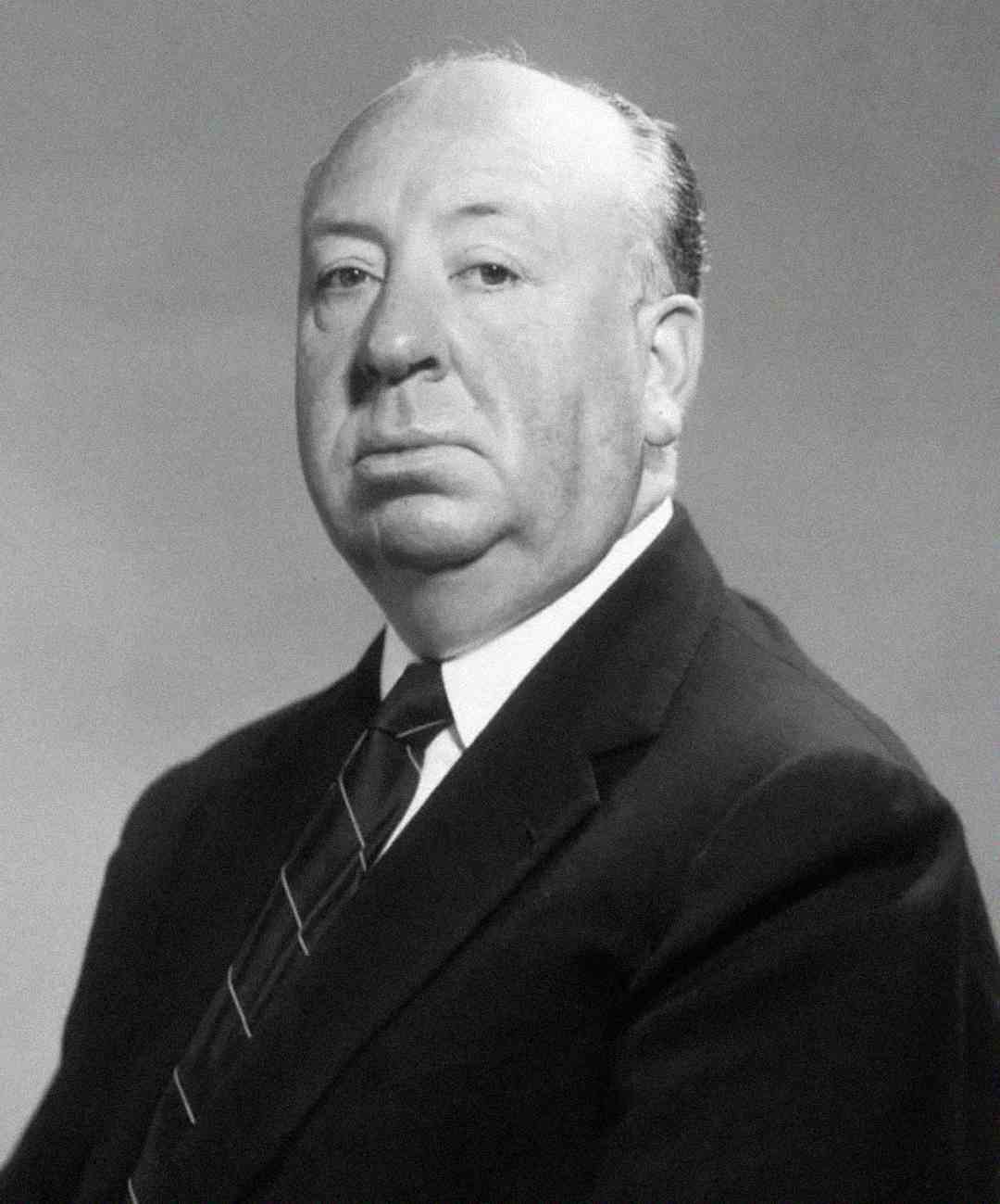 A black and white portrait of a middle-aged man in a suit and tie, facing the camera with a neutral expression against a plain background.