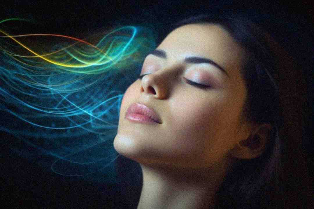 A woman with closed eyes appears calm, with colorful light trails swirling around her face against a dark background, suggesting a sense of peace, meditation, or connection with energy.