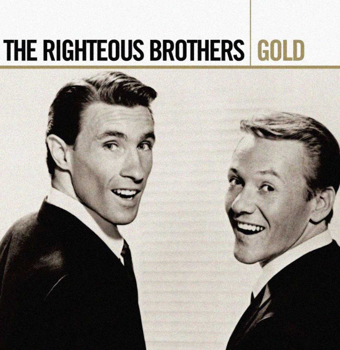 Two men in suits, smiling and looking over their shoulders, appear on the cover of an album titled “The Righteous Brothers Gold.” The background is light, and the image has a vintage black-and-white style.