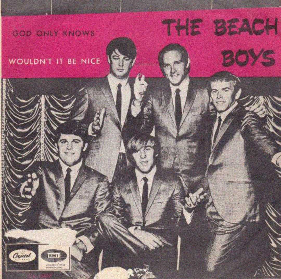 Black-and-white photo of five men in suits posing together, smiling and gesturing, with “The Beach Boys” and song titles “God Only Knows” and “Wouldn’t It Be Nice” written above on a pink and gray background.