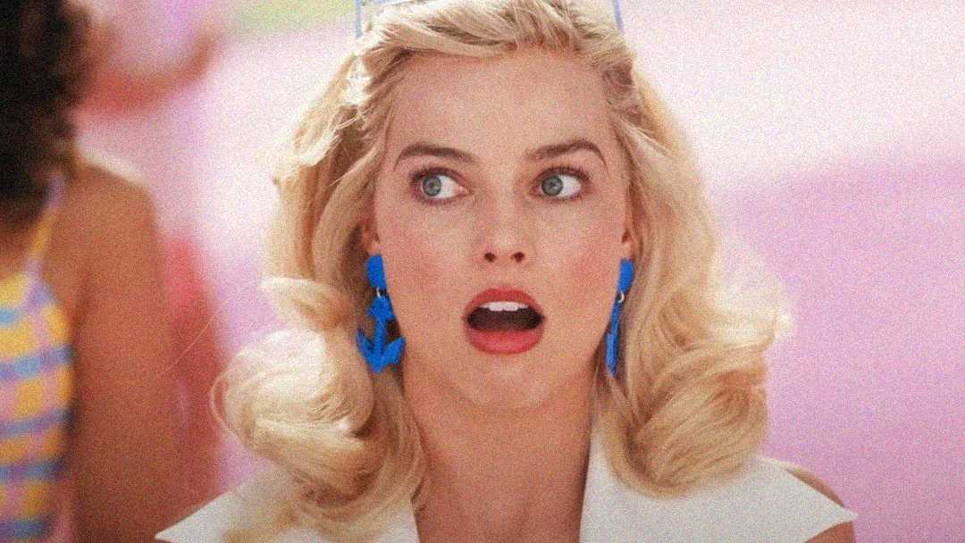 A blonde woman with styled hair, bright red lipstick, and blue earrings looks surprised with her mouth open against a colorful, pastel background.