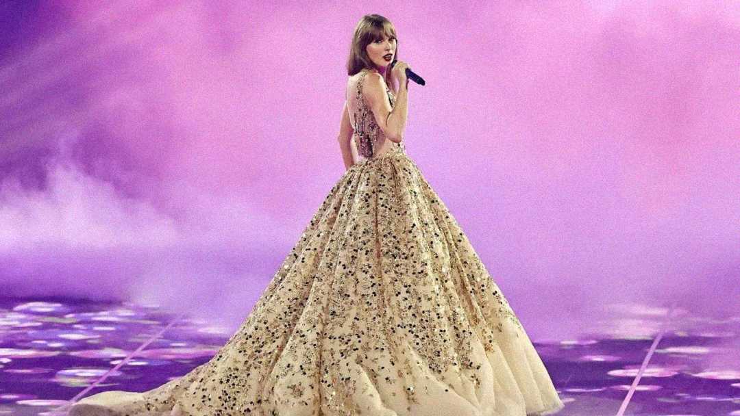 A woman in a sparkling, full-length ball gown sings into a microphone on stage, surrounded by pink and purple mist and dramatic lighting.