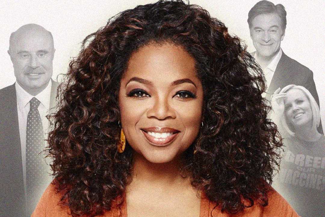 A woman with curly hair smiles in the foreground, wearing an orange top. Three people are shown in faded grayscale behind her: two men in suits and a woman in a light sweater, all smiling.
