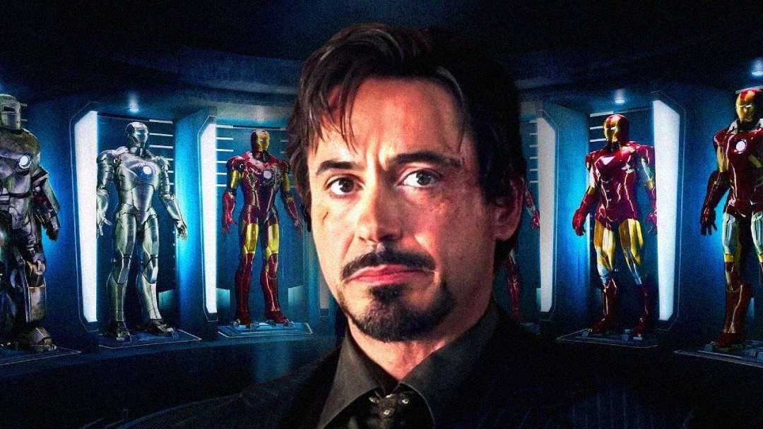 A man with facial hair stands in front of several high-tech armored suits displayed in glass cases, with dramatic lighting highlighting the futuristic setting.
