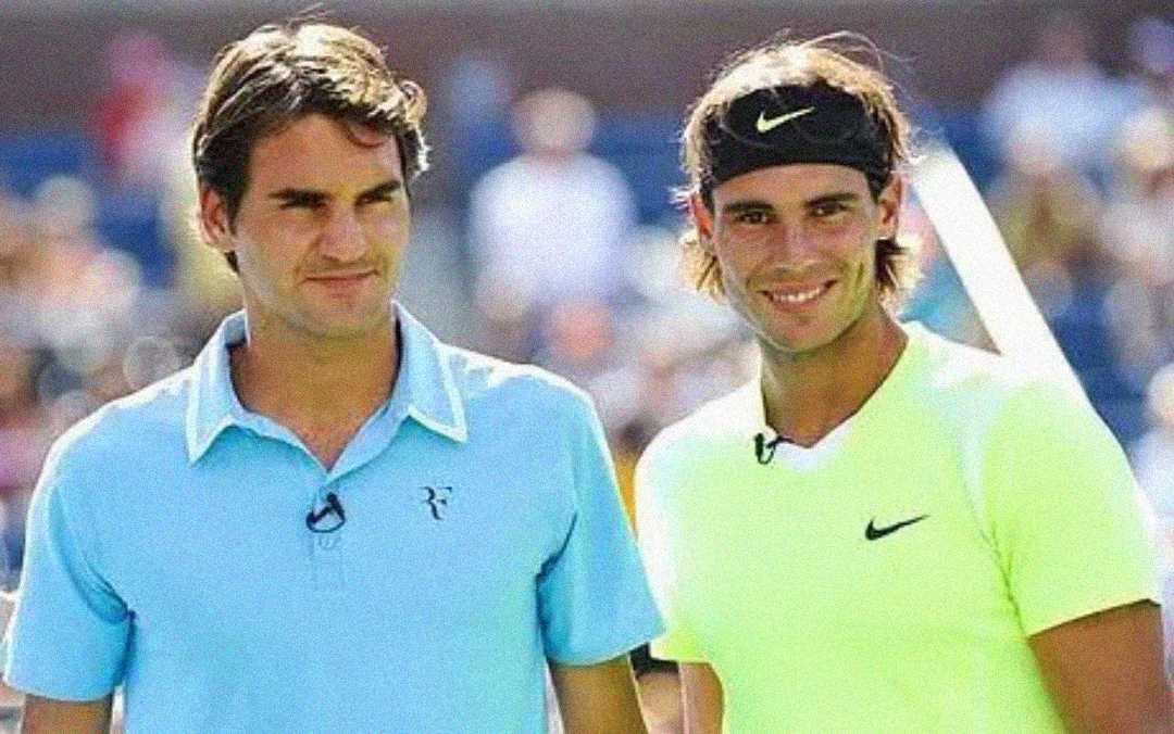 Two male tennis players standing side by side, both smiling. The player on the left wears a light blue polo shirt, and the player on the right wears a bright yellow shirt and a black headband. Tennis court background.