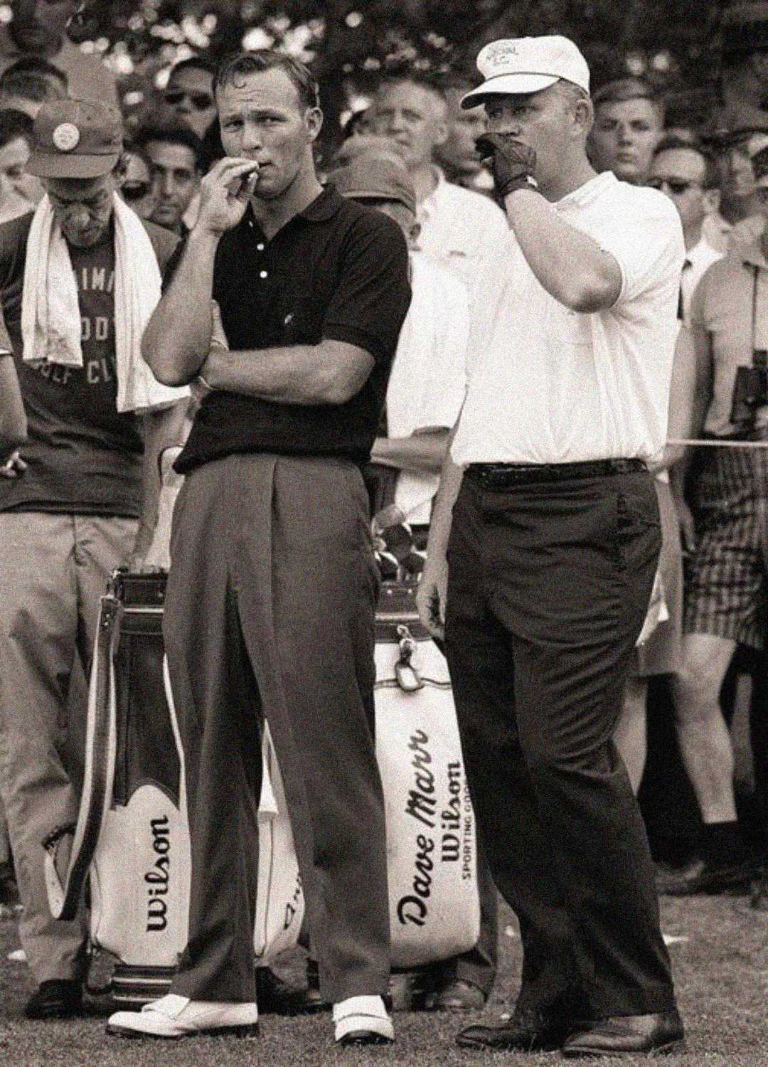 Two male golfers stand side by side on a golf course, both holding cigarettes. They are surrounded by spectators and golf bags labeled "Wilson" and "DAVE MARR." The image is black and white, evoking a vintage feel.