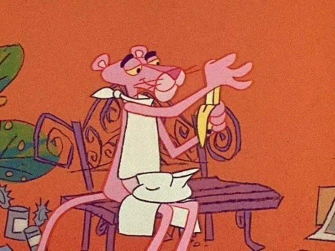The Pink Panther character, wearing a white apron and sitting on a bench, peels a banana with a nonchalant expression against an orange background.