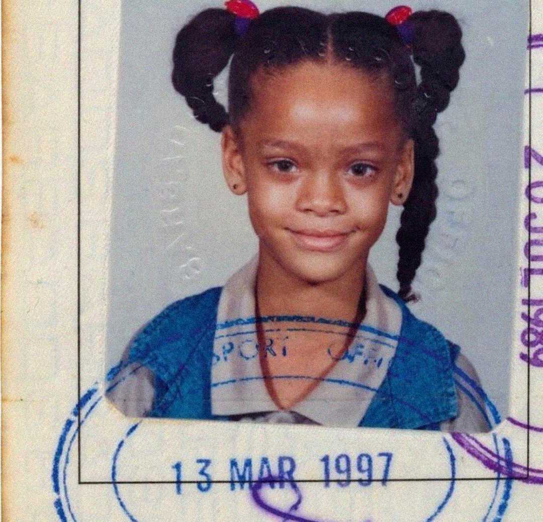 A young girl with braided pigtails, wearing a blue vest over a collared shirt, smiles in a passport-style photo with a blue stamp dated 13 March 1997.