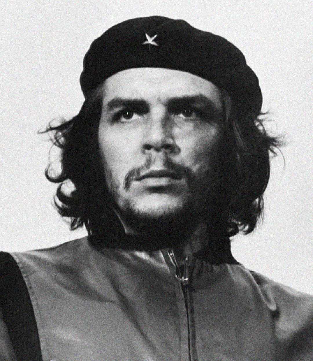 Black-and-white portrait of a man with long hair, a beard, and mustache wearing a beret with a star on it and a zippered jacket, looking intensely into the distance.