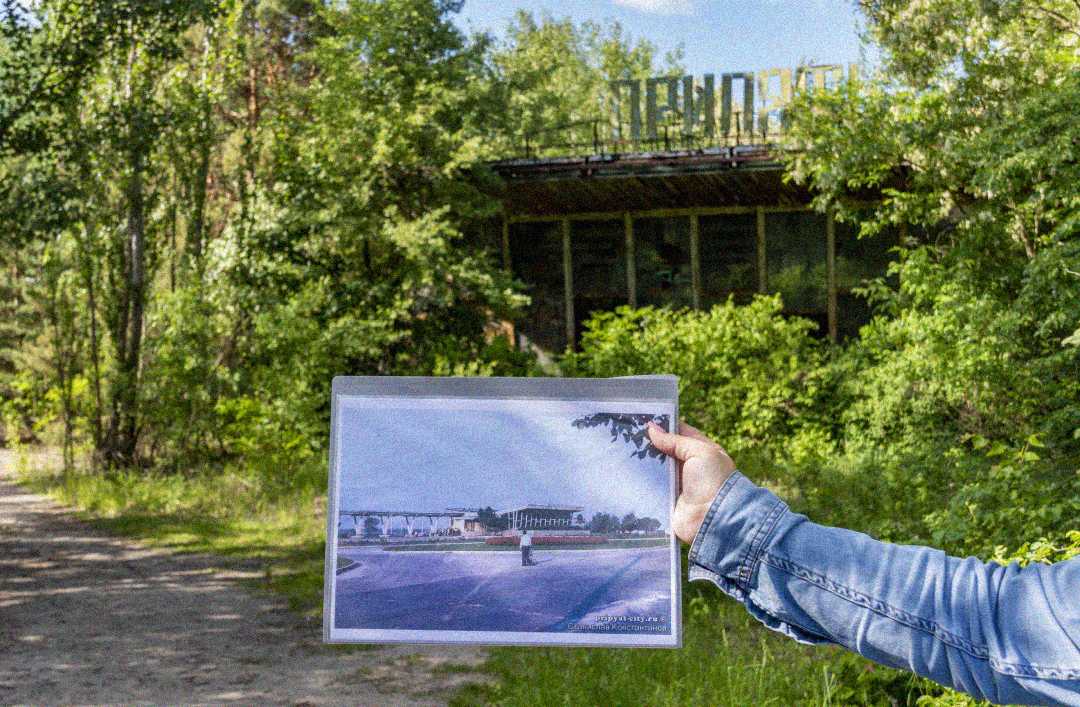A person holds a photo of a once-busy building in front of the same building, now abandoned and overgrown with greenery. The structure is partly obscured by trees and foliage, showing signs of decay.