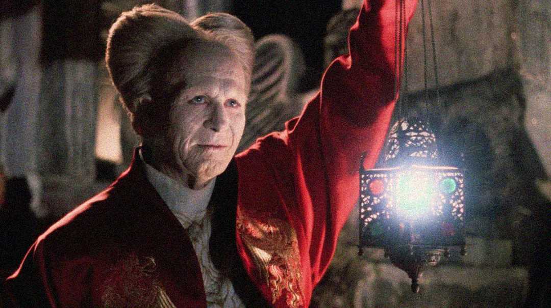 An elderly person with pale skin and elaborate, high white hair wears a red robe and holds up an ornate lantern glowing with blue and green light, standing in a dimly lit, gothic setting.