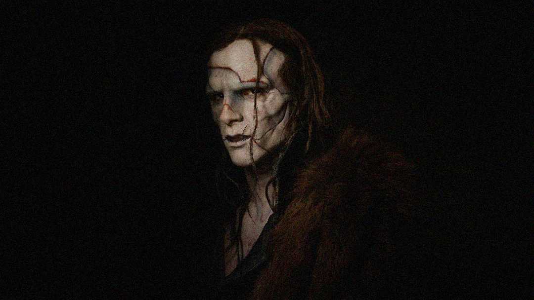 A person with pale makeup, dark eye sockets, and red scars or lines on their face stands against a black background, wearing a fur-collared garment. The overall mood is dark and eerie.