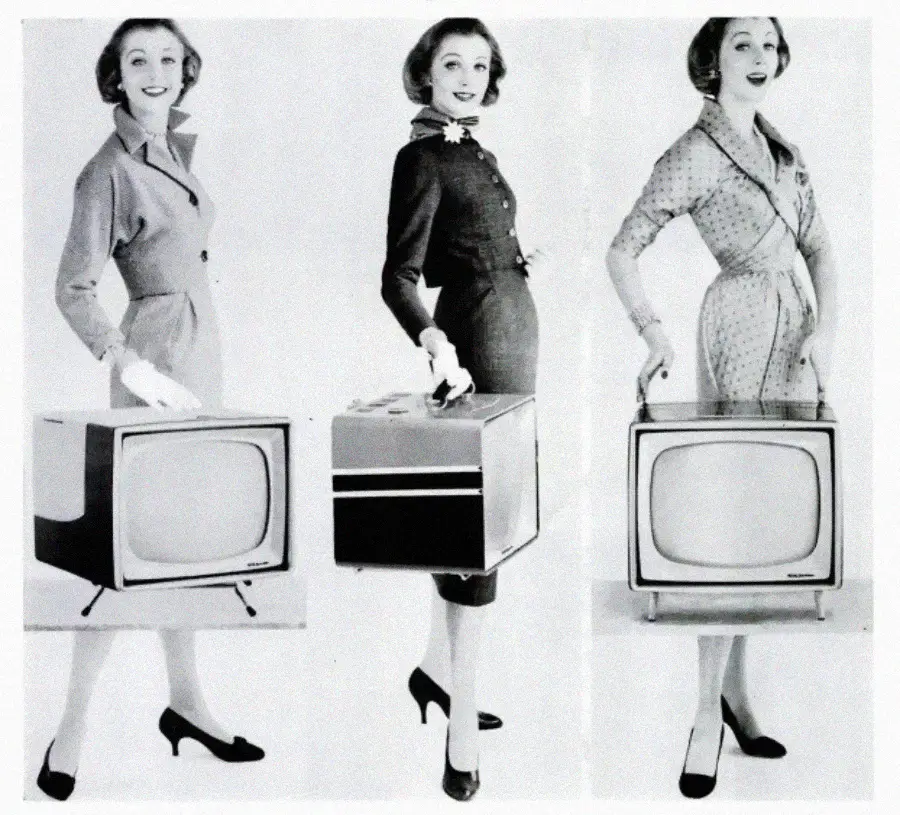 Three women in 1950s-style dresses and heels stand each holding a vintage portable television. The image is black and white, with the women posing and smiling, showcasing the TVs.