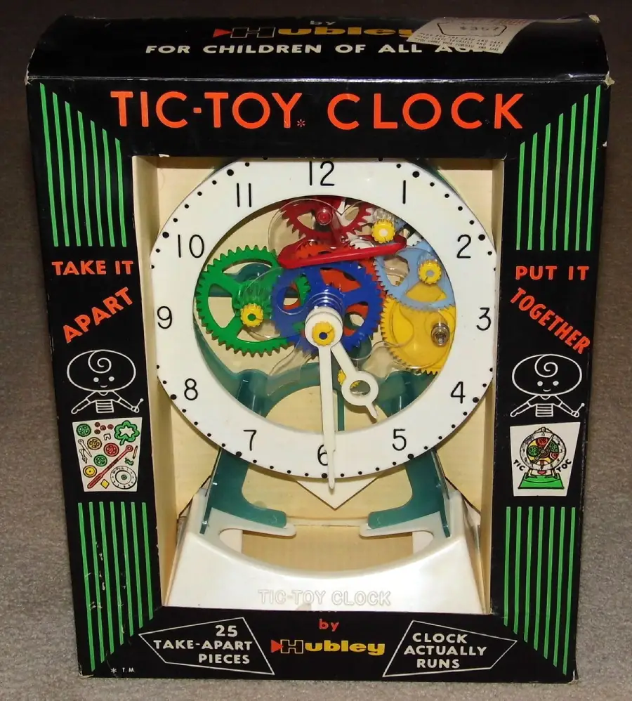 A boxed vintage Tic-Toy Clock by Hubley is shown. The toy clock has visible colorful gears and labeled hands. The packaging says “Take it apart,” “Put it together,” and advertises 25 take-apart pieces and that the clock runs.