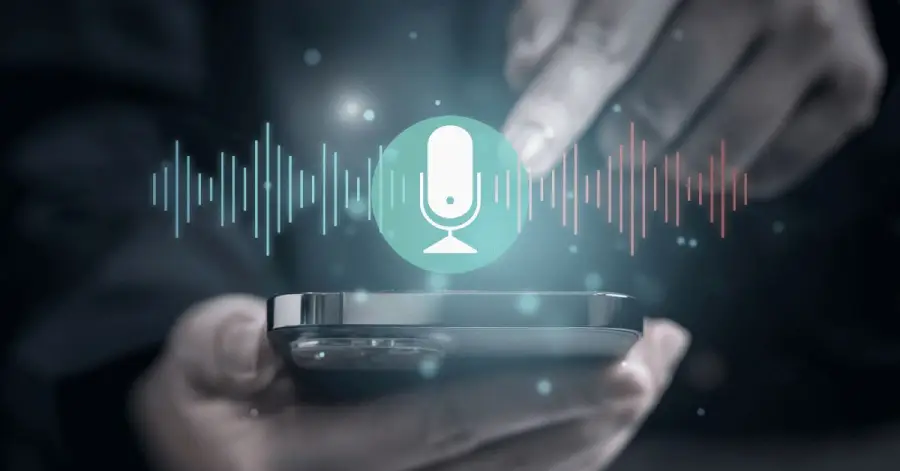 A person uses a smartphone with a glowing voice assistant icon and soundwave graphic hovering above the screen, symbolizing voice recognition technology.