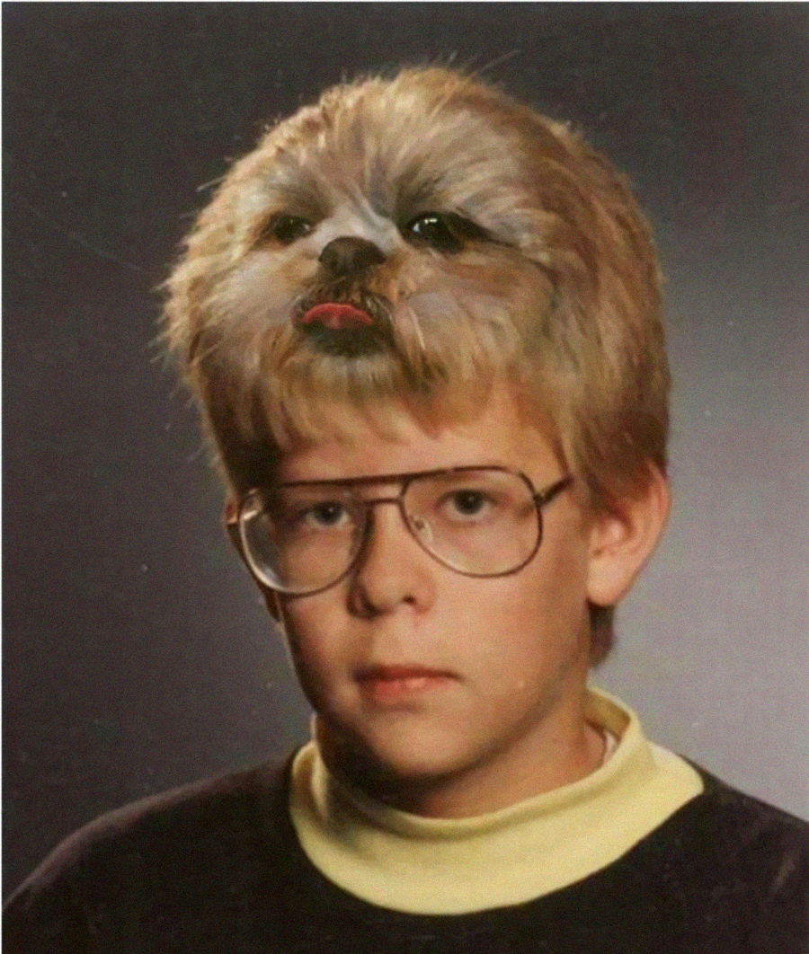 A school portrait of a boy wearing glasses, with a dog's face humorously edited into his hair, making it appear as if the dog's face is part of his head.
