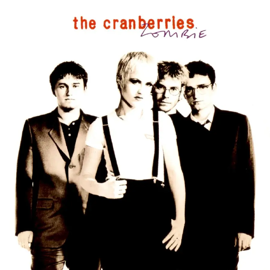 Four band members stand together posing for a black-and-white photo. "The Cranberries" is written in red text above them, with "Zombie" handwritten in black. The woman in front has short blonde hair and wears suspenders.
