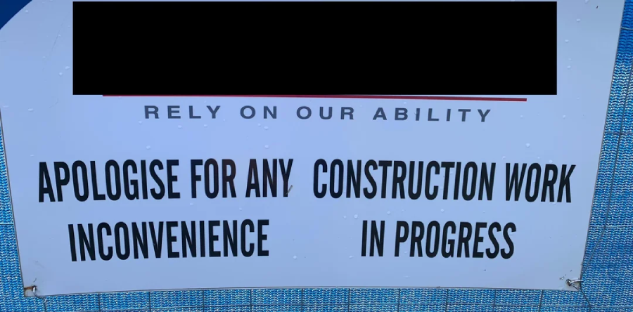 A construction sign reads: "APOLOGISE FOR ANY INCONVENIENCE. CONSTRUCTION WORK IN PROGRESS." The top section with a company name is blacked out. The background is blue.