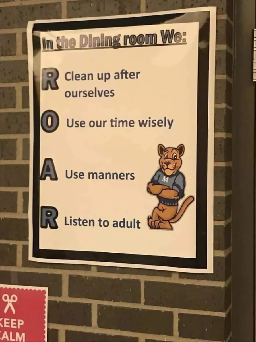 A poster on a brick wall lists dining room rules using the acronym ROAR: Clean up after ourselves, Use our time wisely, Use manners, Listen to adult. A cartoon lion mascot in blue stands next to the list.