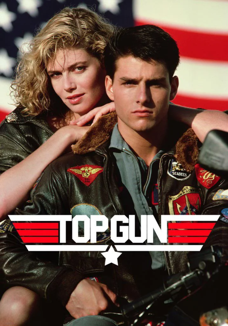 A man and woman in aviator jackets pose in front of an American flag. The man looks serious, and the woman rests her hands on his shoulders. Bold text reads "Top Gun" with red stripes and a white star beneath.
