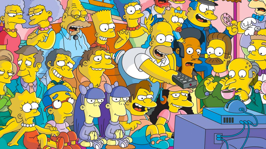 A group of characters from The Simpsons, including Homer, Marge, Bart, Lisa, and others, gather in a colorful room, watching television together. Homer is in front, reaching for the remote.