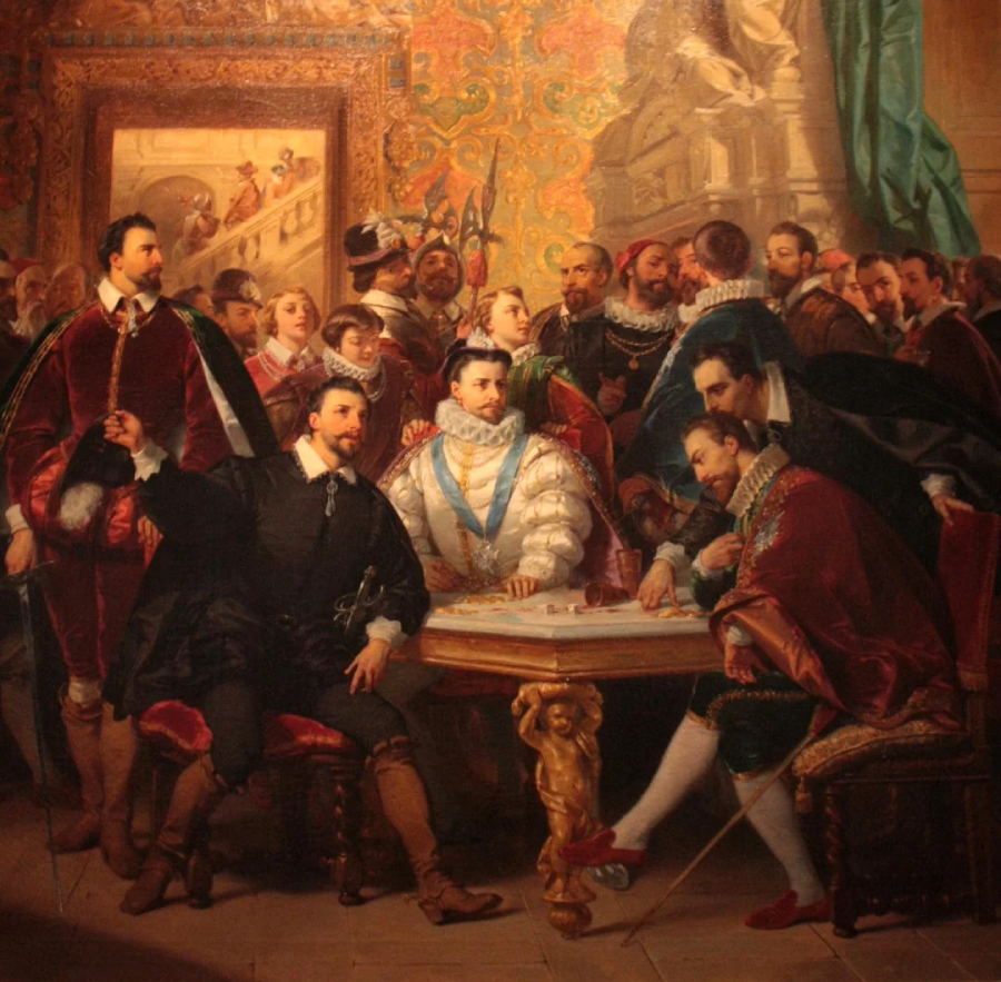 A group of elaborately dressed men and women gather around a table in a lavishly decorated room, engaged in discussion, with ornate walls and a statue in the background.