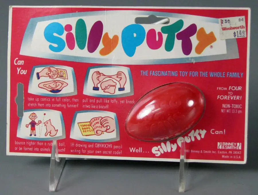 A vintage Silly Putty toy package shows a red egg-shaped container and colorful text. Illustrations demonstrate how to use the putty to copy comics and stretch images. Price stickers are visible in the top right corner.