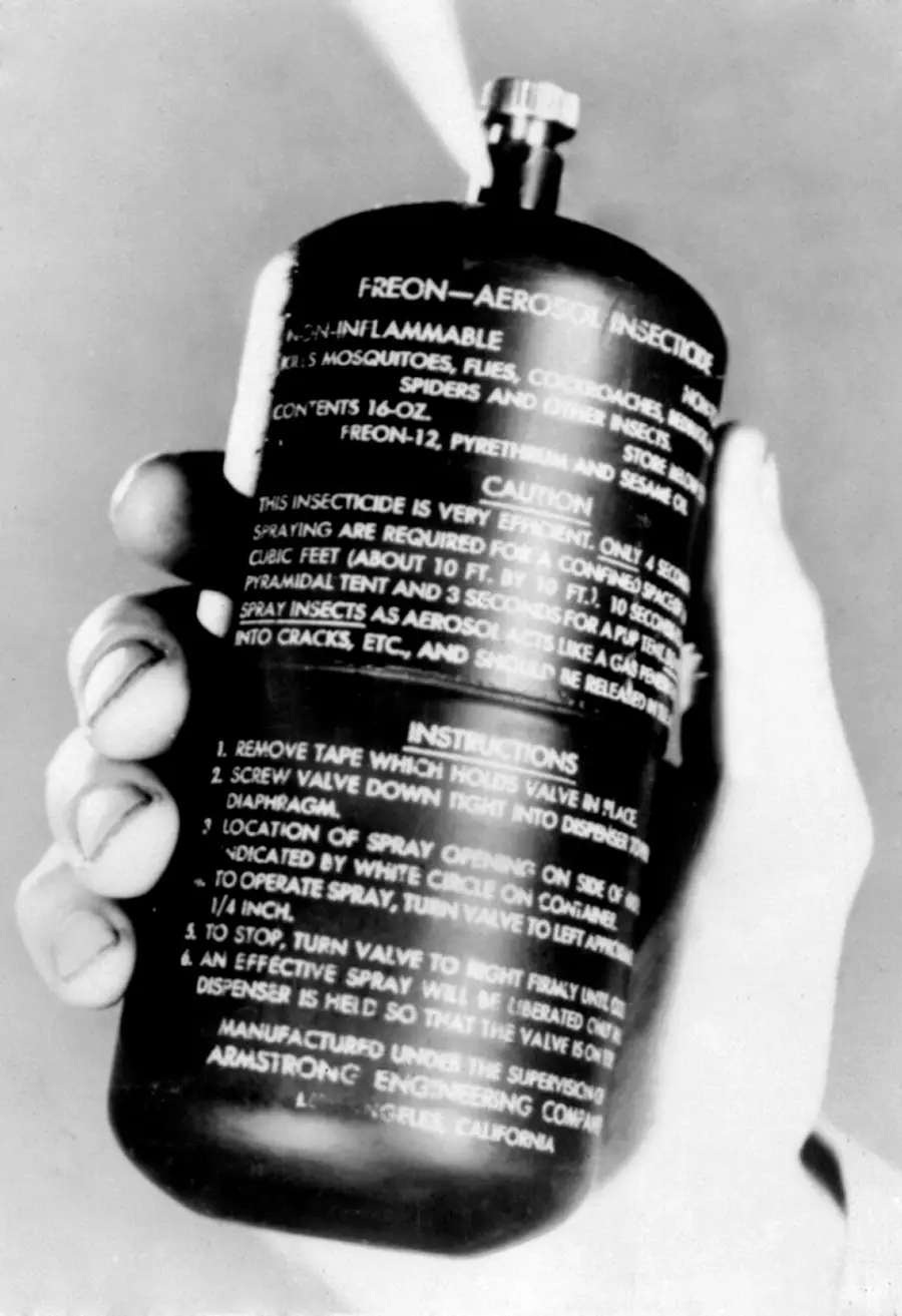 A hand holds a can of Freon-aerosol insecticide with white text detailing cautions, instructions, and product information. The spray is being released from the top of the can.