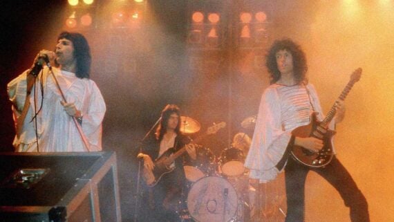Queen performing live on stage featuring Freddie Mercury, Brian May, Roger Taylor, and John Deacon.