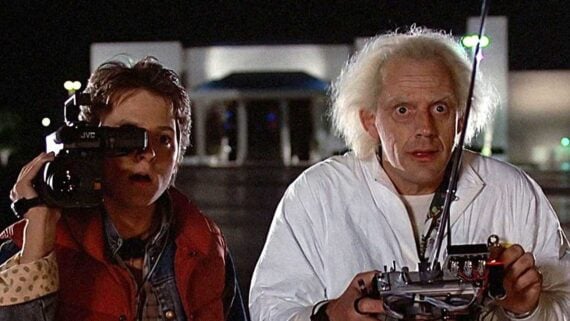 Doc Brown and Marty McFly standing beside the DeLorean in a promotional image from Back to the Future.