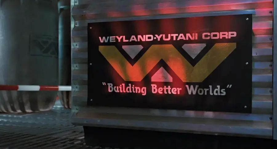 A metal wall displays a large sign reading "Weyland-Yutani Corp" with a gold and black logo and the slogan "Building Better Worlds" in quotes. Industrial containers and pipes are visible in the background.