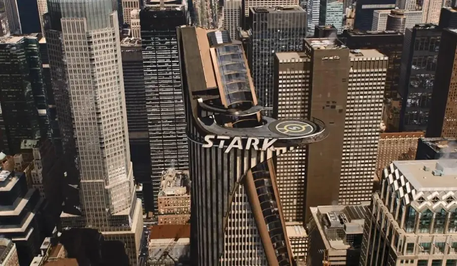 A futuristic skyscraper labeled "STARK" with a helipad on its rooftop stands among other high-rise buildings in a cityscape, resembling New York City.