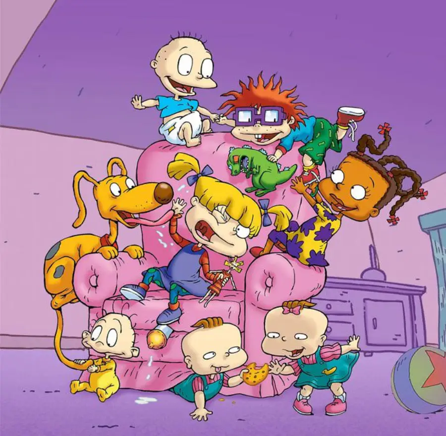Cartoon babies and a dog play on and around a large pink armchair in a room, with toys scattered on the floor. The scene is lively and colorful, showing excitement and playful chaos.