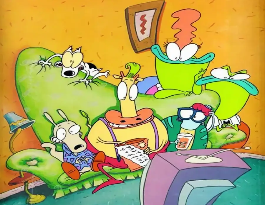 A group of colorful cartoon characters, including a wallaby, cow, turtle, dog, and two frogs, sit on a green couch watching TV in a quirky, brightly decorated living room.