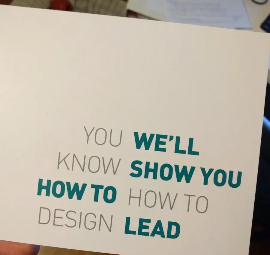 A card with mixed black and blue text that reads: "YOU'LL KNOW HOW TO DESIGN" and "WE'LL SHOW YOU HOW TO LEAD," with each sentence split and words in alternating colors.