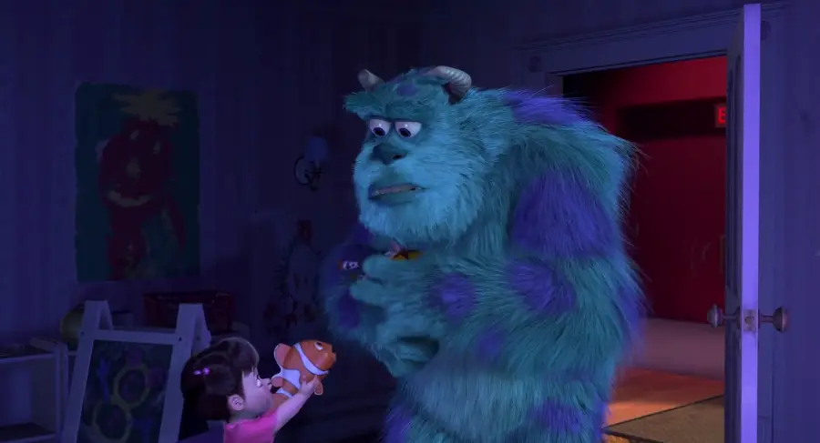 A young girl hands a plush clownfish toy to a large blue and purple monster inside a dimly lit room with an open door in the background.