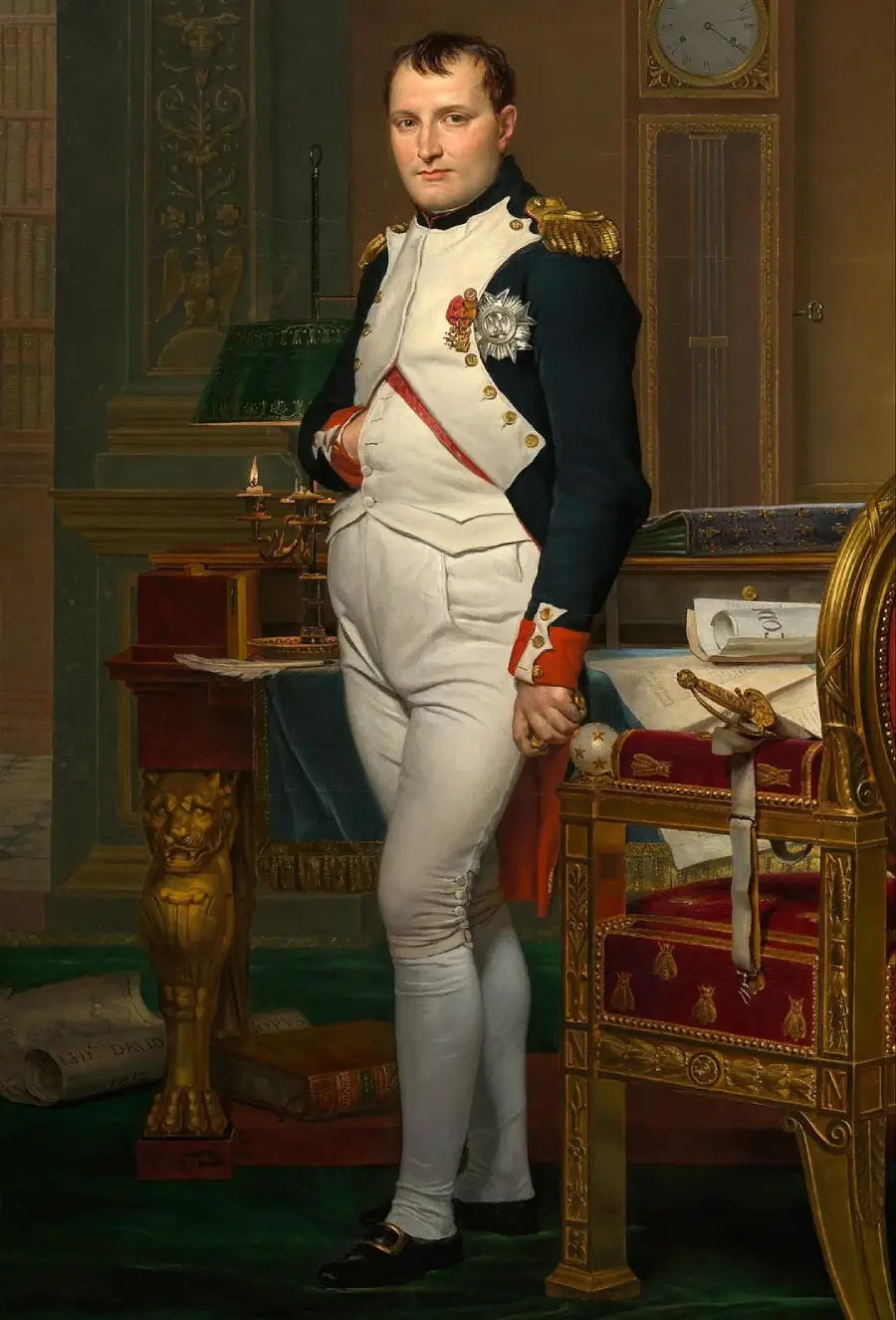 A man in a military uniform stands beside a desk with books, papers, and a clock in the background; he has one hand inside his jacket and looks directly at the viewer in an ornate, historical setting.