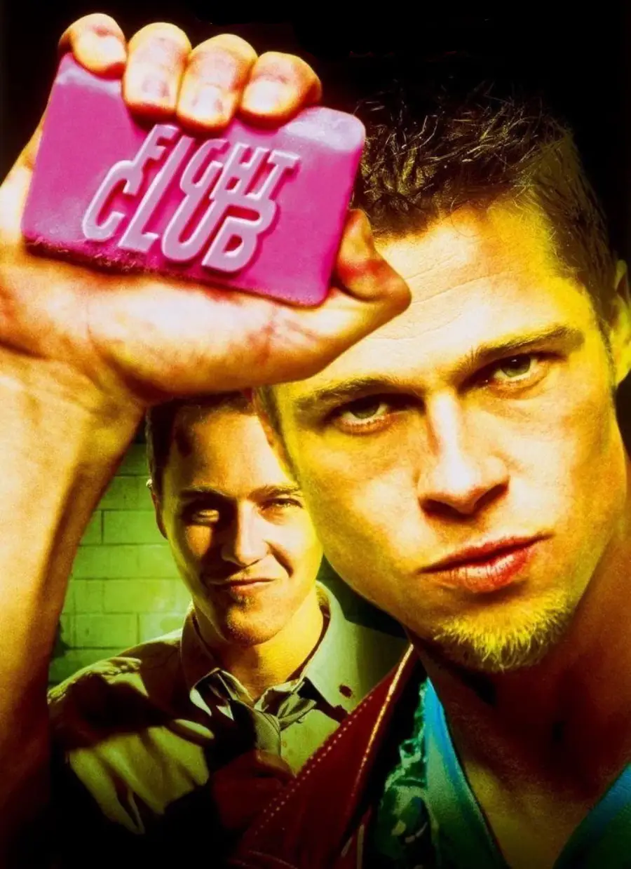 Two men stand close together; the man in front holds up a pink bar of soap labeled "FIGHT CLUB" and stares intensely at the camera, while the man behind him looks on with a smirk.