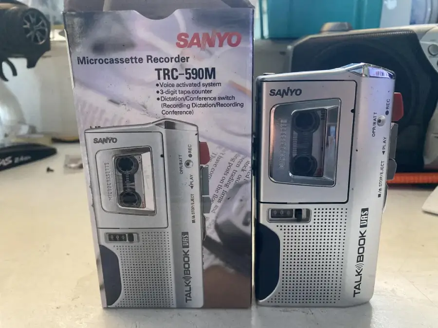 A Sanyo microcassette recorder TRC-590M is shown next to its box. The box displays an image of the recorder and features like voice-activated system, 3-digit tape counter, and various recording modes.