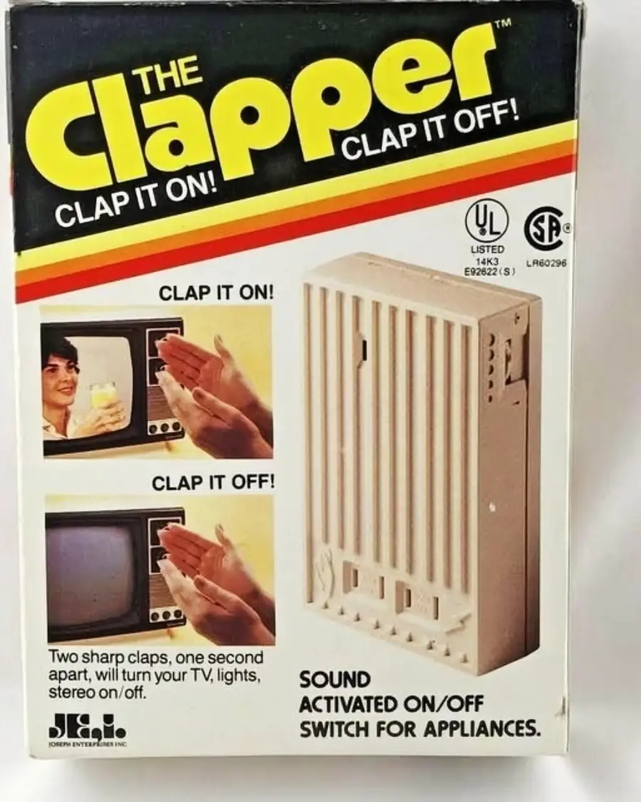 Box for "The Clapper" sound-activated on/off switch, featuring images of hands clapping to control appliances like a TV, with text reading "Clap it on! Clap it off!" and a picture of the device.