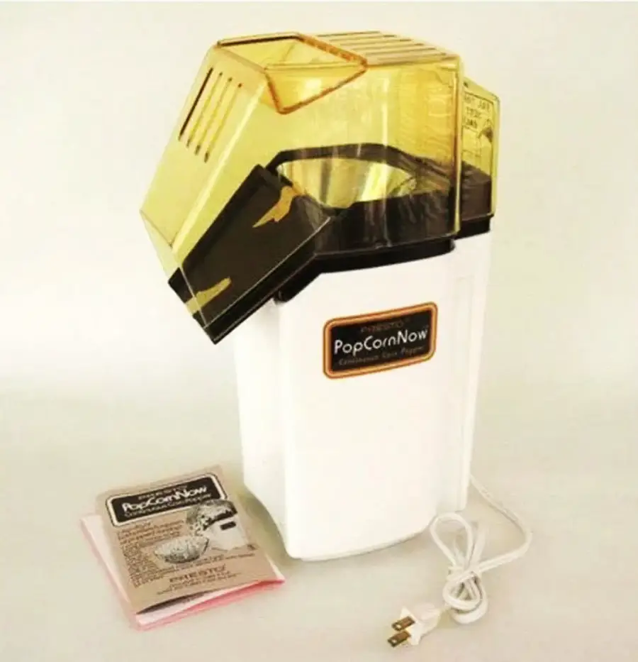 A white electric popcorn maker with a yellow transparent lid is shown next to its instruction manual. The appliance has a power cord and a label reading “PopCornNow” on the front.